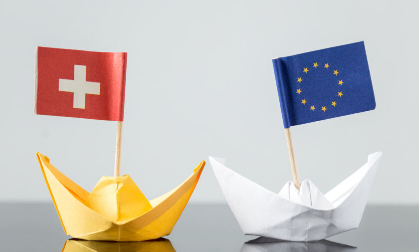 Papierschiffchen mit EU und Schweiz Flagge in Bewegung